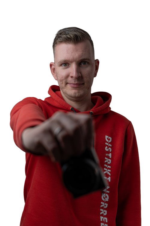 Een portret foto van Jan Doornbos die een camera voor zijn borst houdt